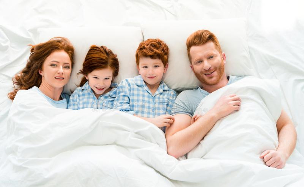 Счастливая семья в пижамах лежит в постели